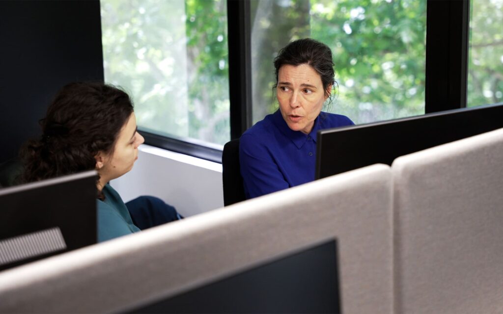 Two professionals working on a computer in a modern office environment